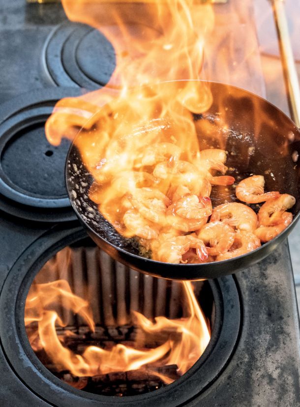 Cuisson d'un plat de crevettes sur un fourneau à bois
